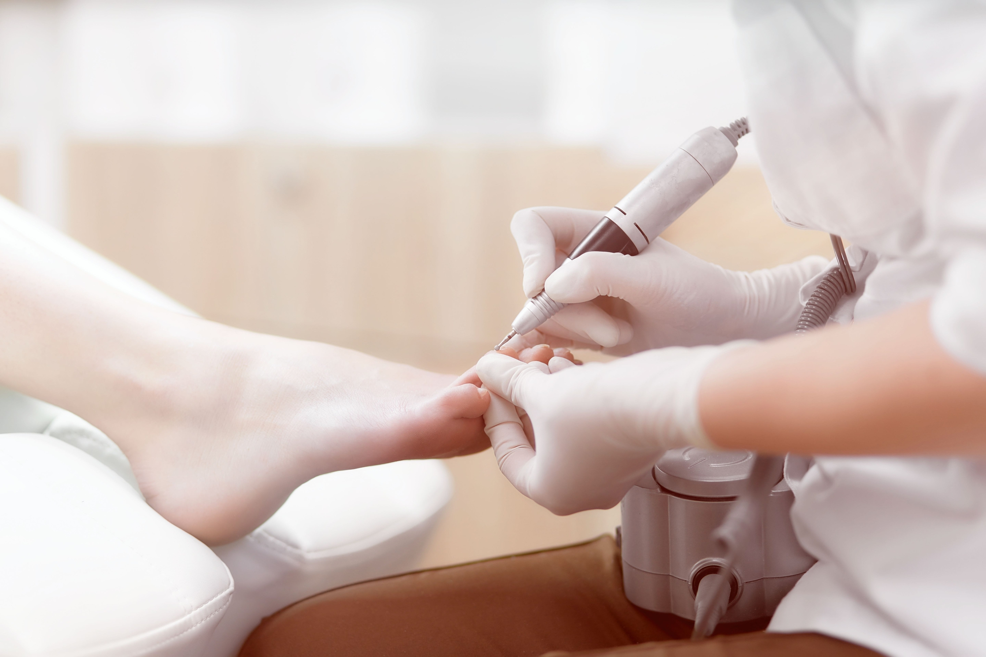 Doctor in gloves making procedure for foot with special equipmen